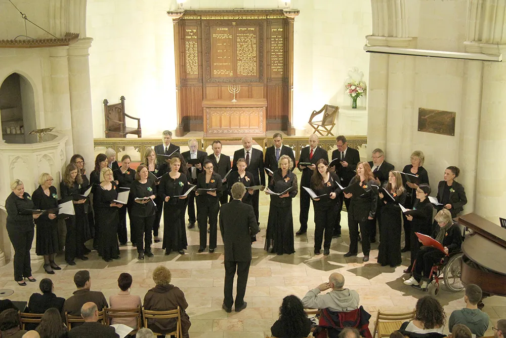 Der Zamirchor singt in einem hellen Kirchenraum, vorne der Dirigent, dahinter Tafeln mit hebräischer Schrift